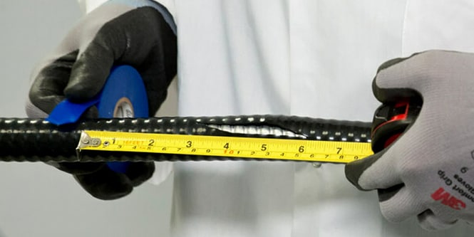 worker measuring electrical cable and marking with blue electrical tape
