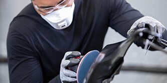 collision technician sanding filler on panel of car
