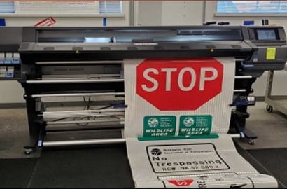 a red traffic 'stop' sign being printed on a commercial digital printer.