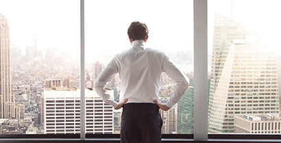 A male employee stands comfortably near an office window covered with 3M Sun Control Window Film.
