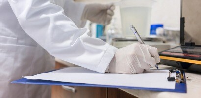 Lab technician writing on a document on a clipboard
