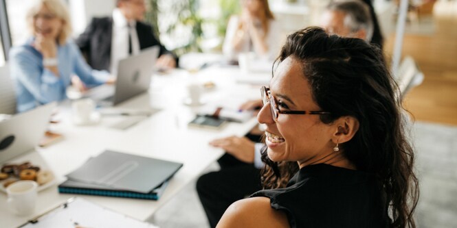 Female executive sitting at a large table with other executive discussing corporate governance.
