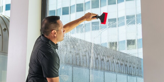 Person applying window film with a squeegee.

