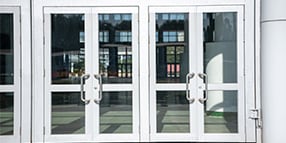 Exterior photo of building entrance with two sets of glass double doors
