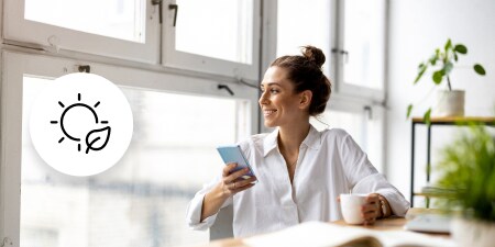 Person seated beside large windows holding a phone, with sun and leaf icon overlay.
