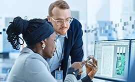 Two people looking intently at a phone.
