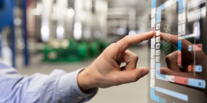 Image of a factory worker utilizing a touchscreen display on the assembly line.
