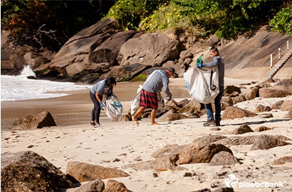 A group of people cleaning up trash on the beach.