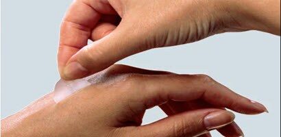close-up of fingers lifting medical adhesive from skin on back of hand
