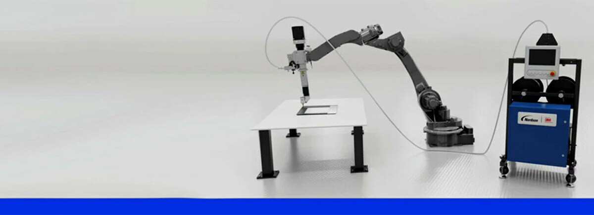 Image of the 3M™ On Demand Bonding System, including a workpiece on a table, robot arm and dispensing stand
