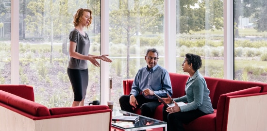Three people talking in a conference workspace.
