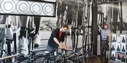 man adjusting bikes in a shop against a wall graphic to help promote brand experience.