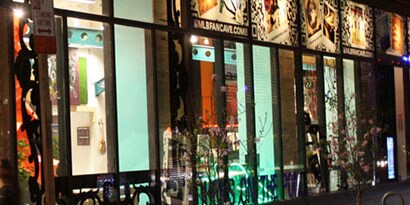 A storefront at nighttime has a bright interior and windows with window graphics.
